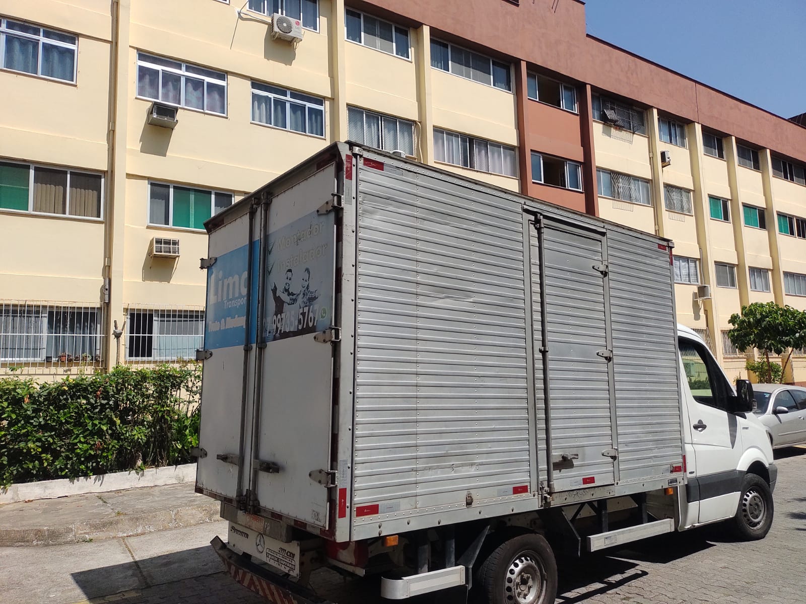 Sprinter baú com o adesivo da Lima Transporte estacionada em frente a um prédio residencial